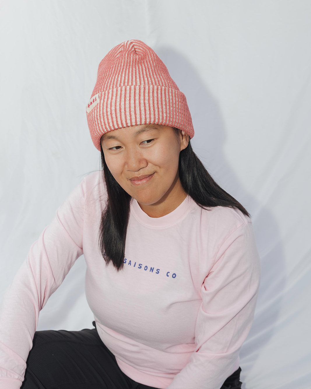 Person wearing a pink beanie and sweater against a white background