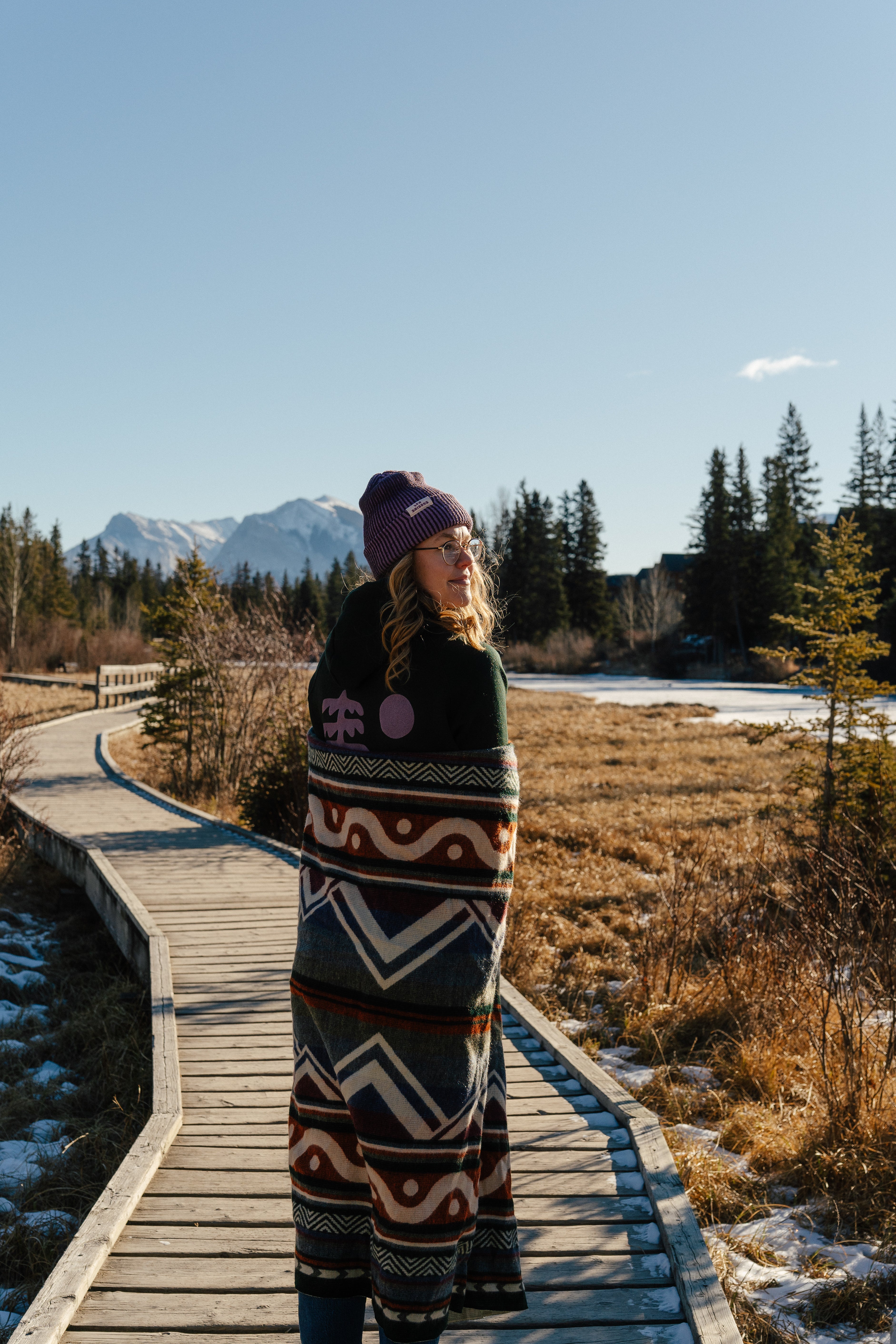Blanket, shades of blue, orange, lightweight, mountain designs, handcrafted in Ecuador, Acrylic, durable, 70" x 48", soft, camping, van life, outdoors, lifestyle, Les Saisons, Marine Poiraton ski Blanket Mountains orange and green.