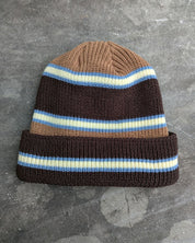 Brown and blue retro striped beanie with a les Saisons tag on a gray concrete surface, made in Canada.