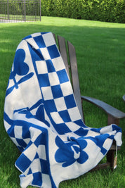 Blue and white checkered blanket with flower design on a chair with grassy surface