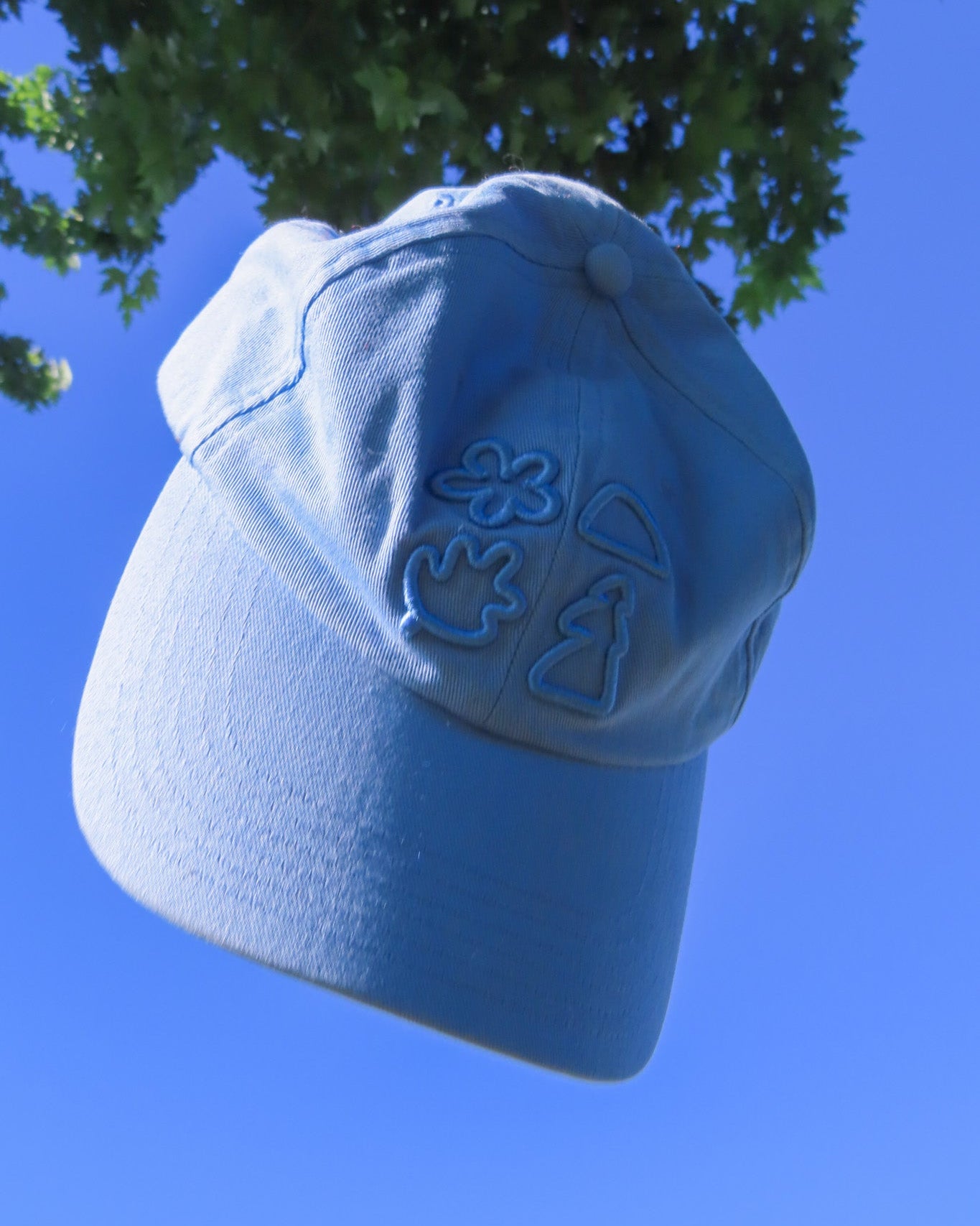 Blue cap with embroidered designs against a clear blue sky