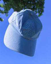 Blue cap with embroidered designs against a clear blue sky