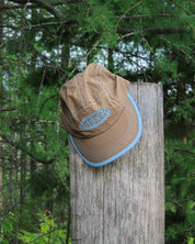Brown cap with blue rim on a wooden post in a forest setting