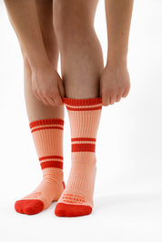 Person wearing pink socks with red stripes on a white background