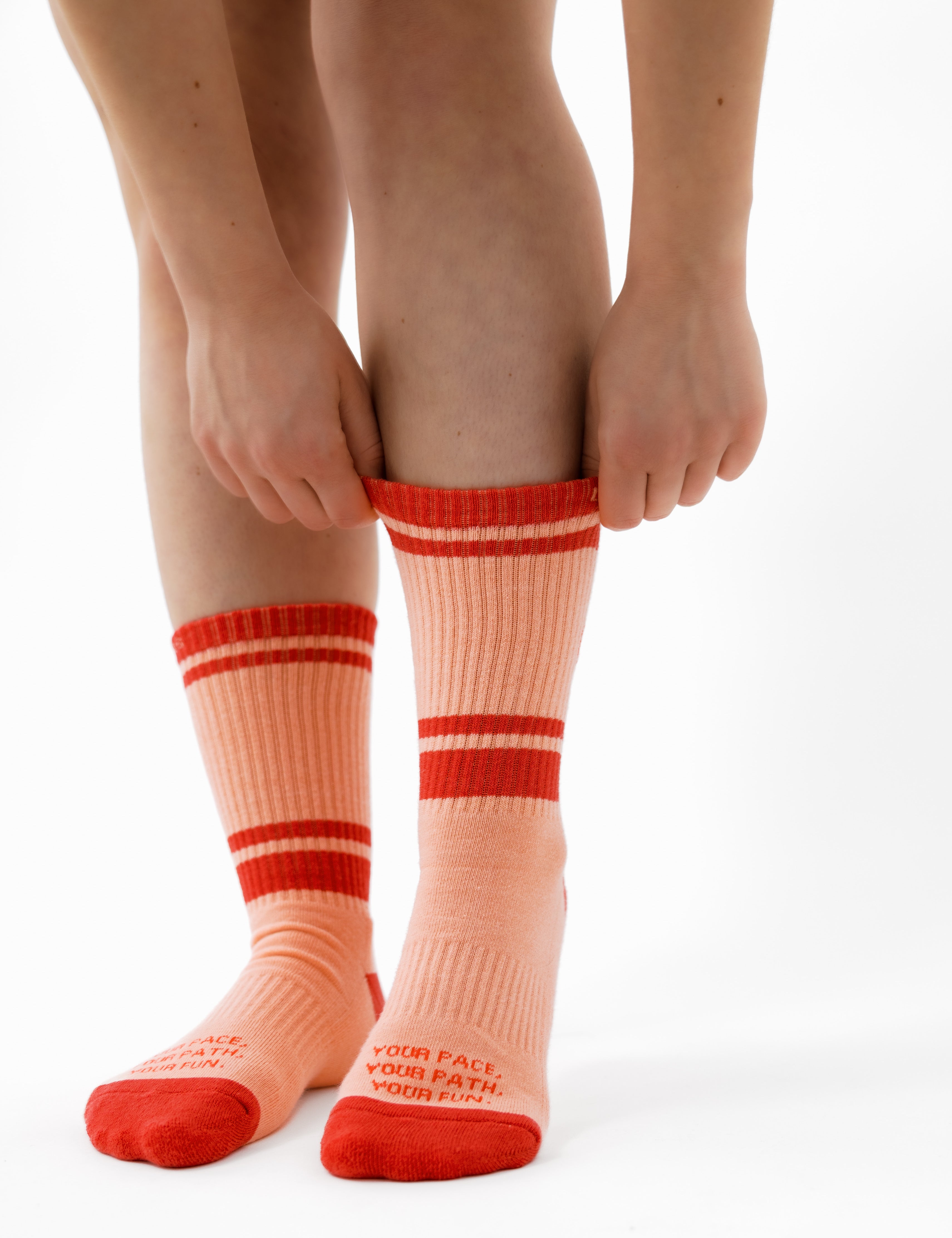 Person wearing pink socks with red stripes on a white background