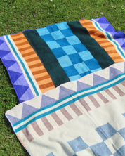 Two patterned blanket on a grassy surface