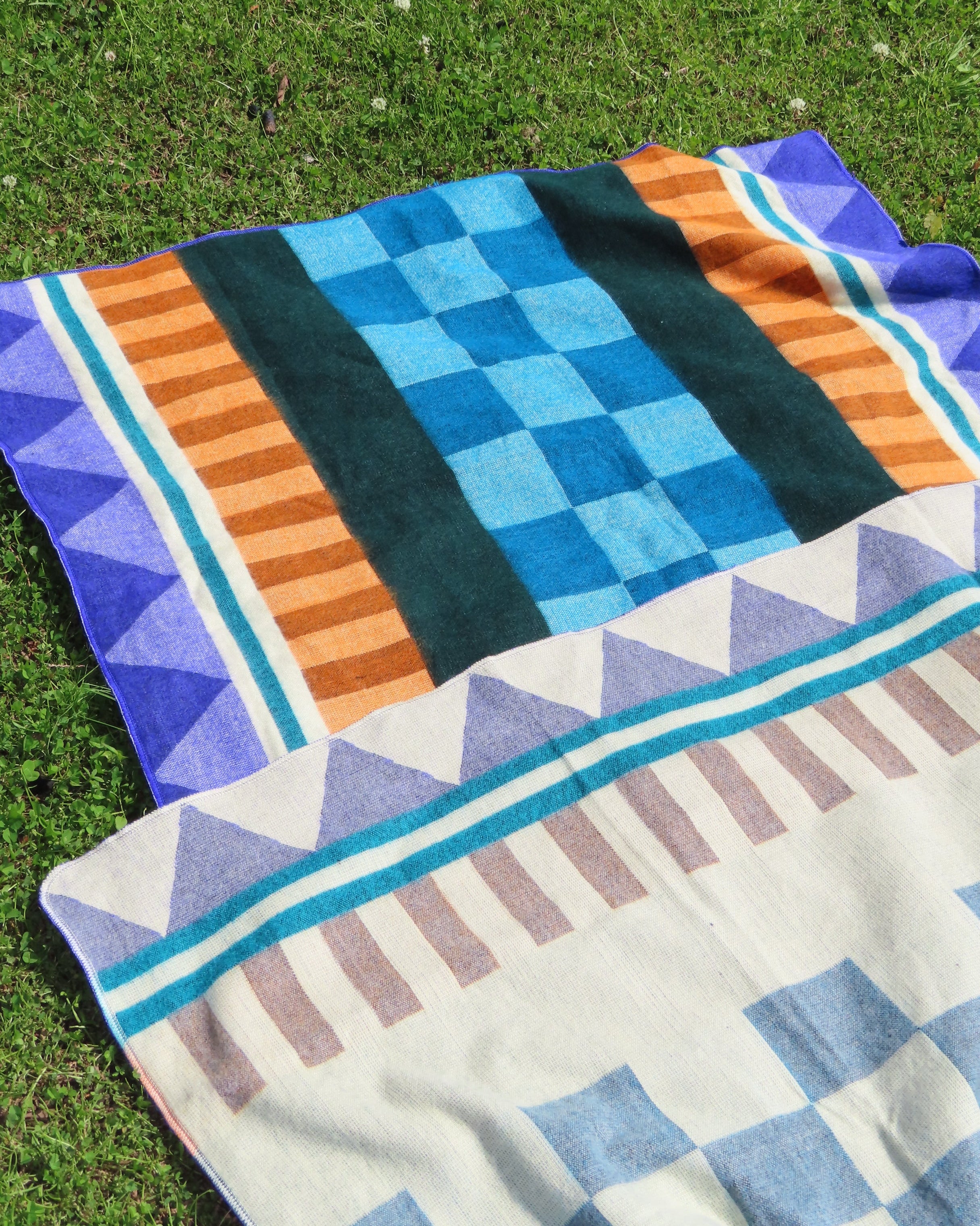 Two patterned blanket on a grassy surface