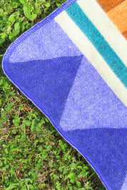 Close-up of a colorful blanket with geometric pattern on grass