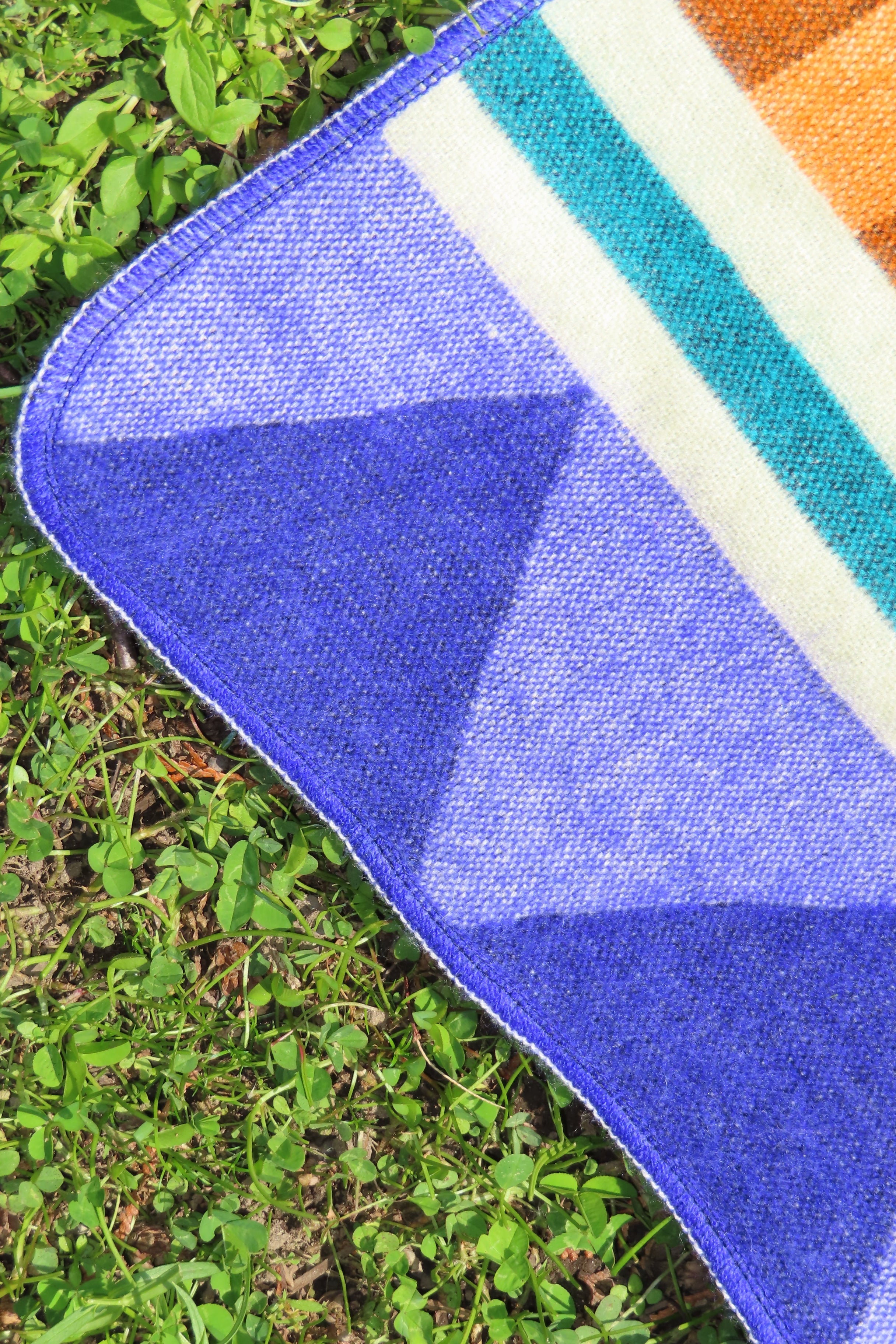 Close-up of a colorful blanket with geometric pattern on grass
