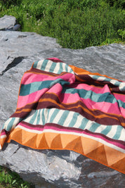 Colorful striped fabric draped over a rock with a natural outdoor background