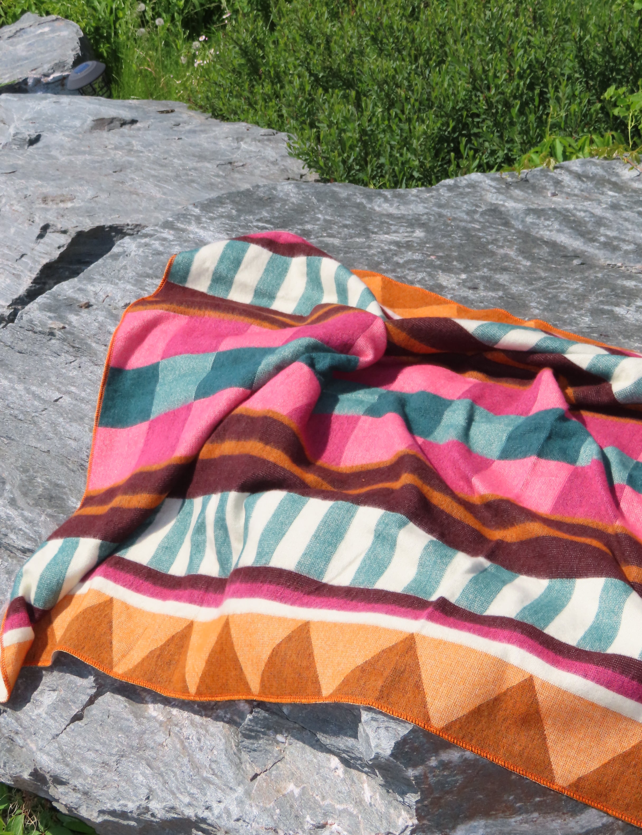 Colorful striped fabric draped over a rock with a natural outdoor background