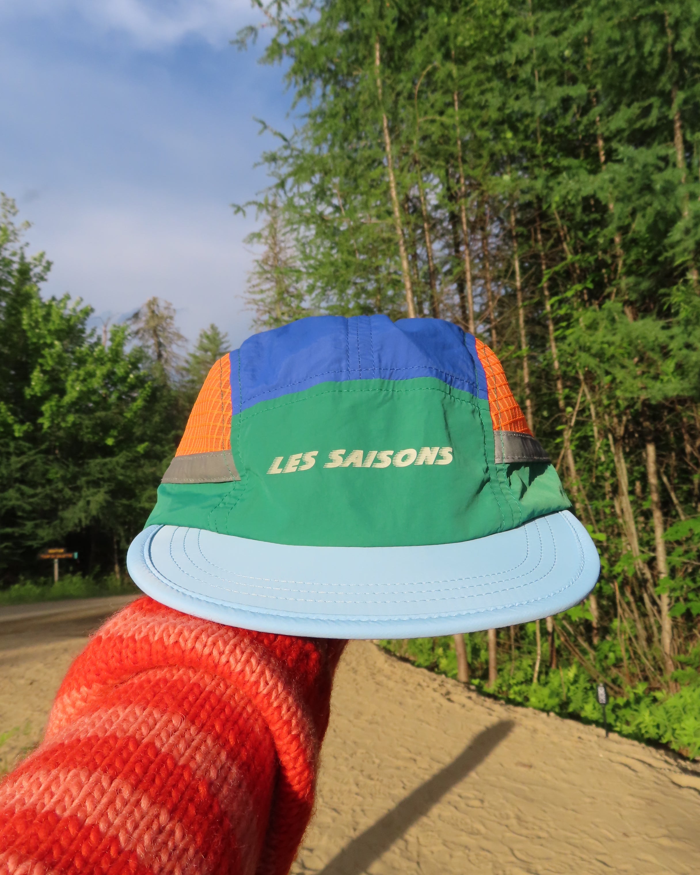 Person holding a colorful cap with a forest backgroun