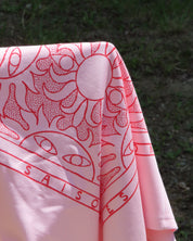 Pink fabric with red pattern against a green grass background