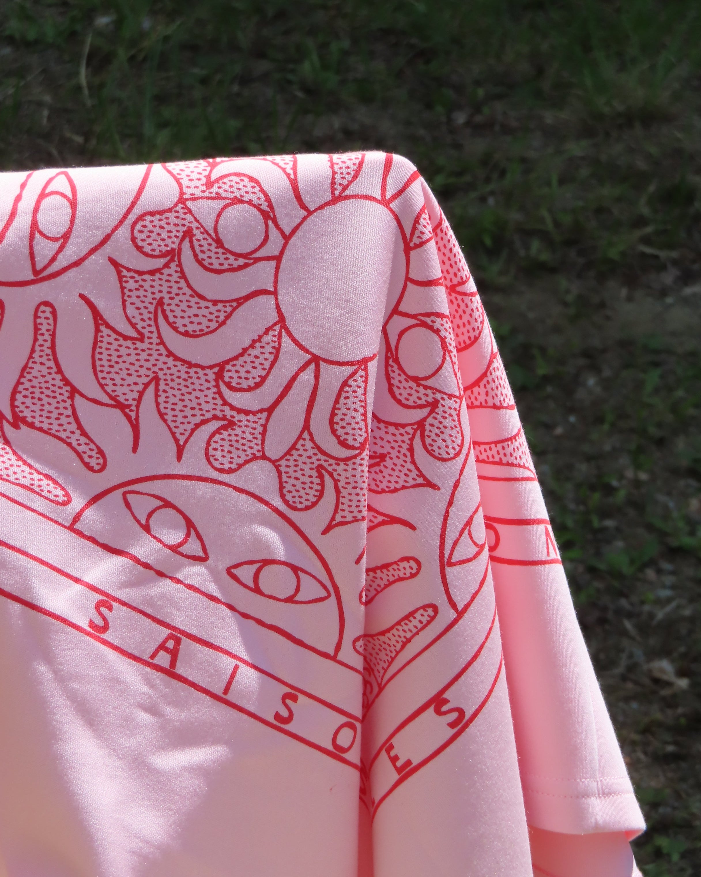 Pink fabric with red pattern against a green grass background