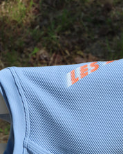 Close-up of a blue tank top with Les Saisons logo on a natural background