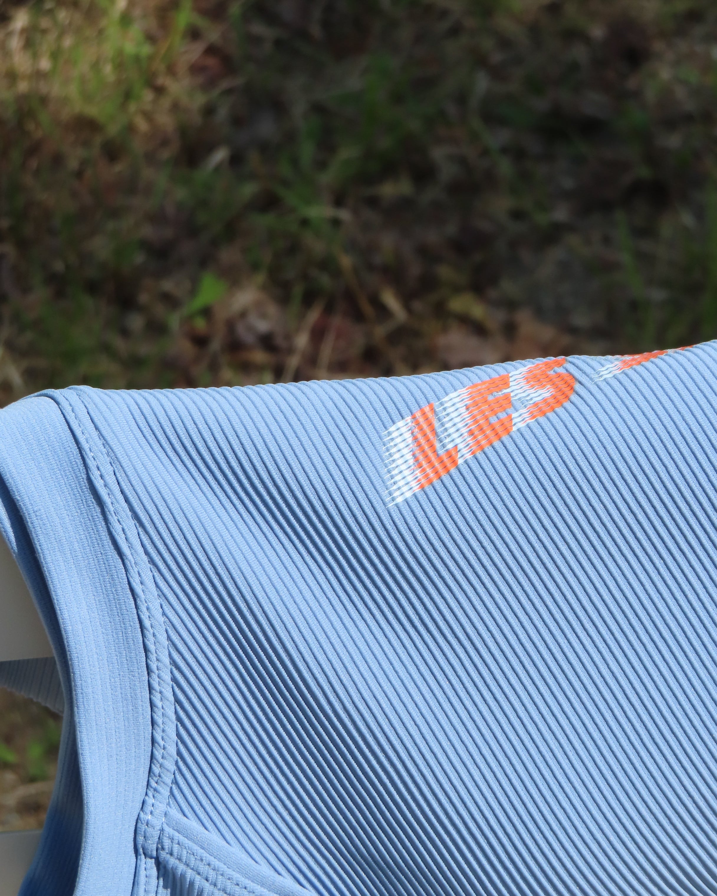 Close-up of a blue tank top with Les Saisons logo on a natural background