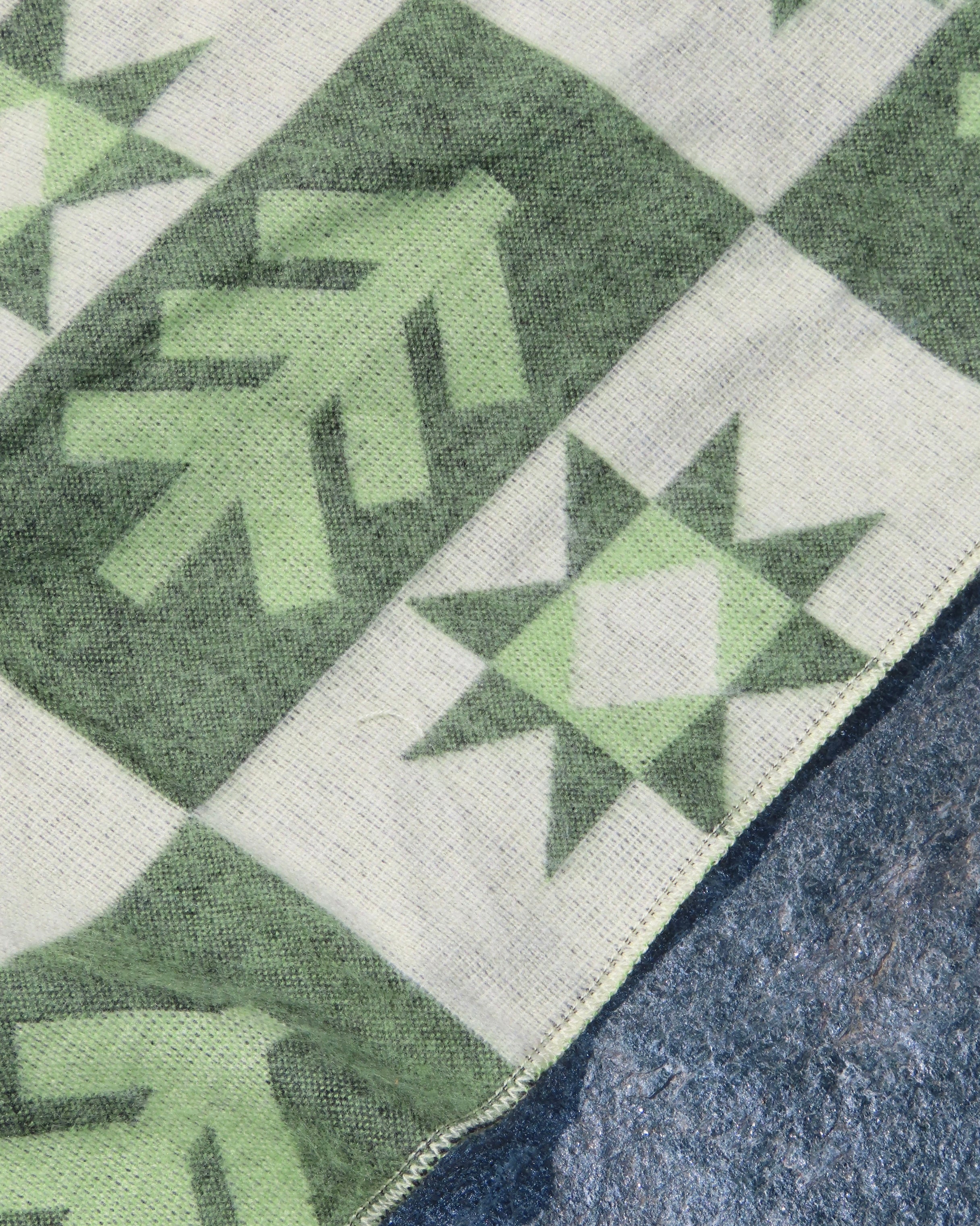 Close up of a green and beige blanket with a foresy pattern