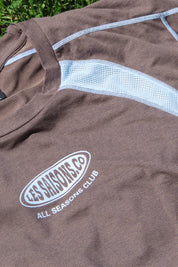Close up of a brown shirt with blue lines and Les Saisons logo