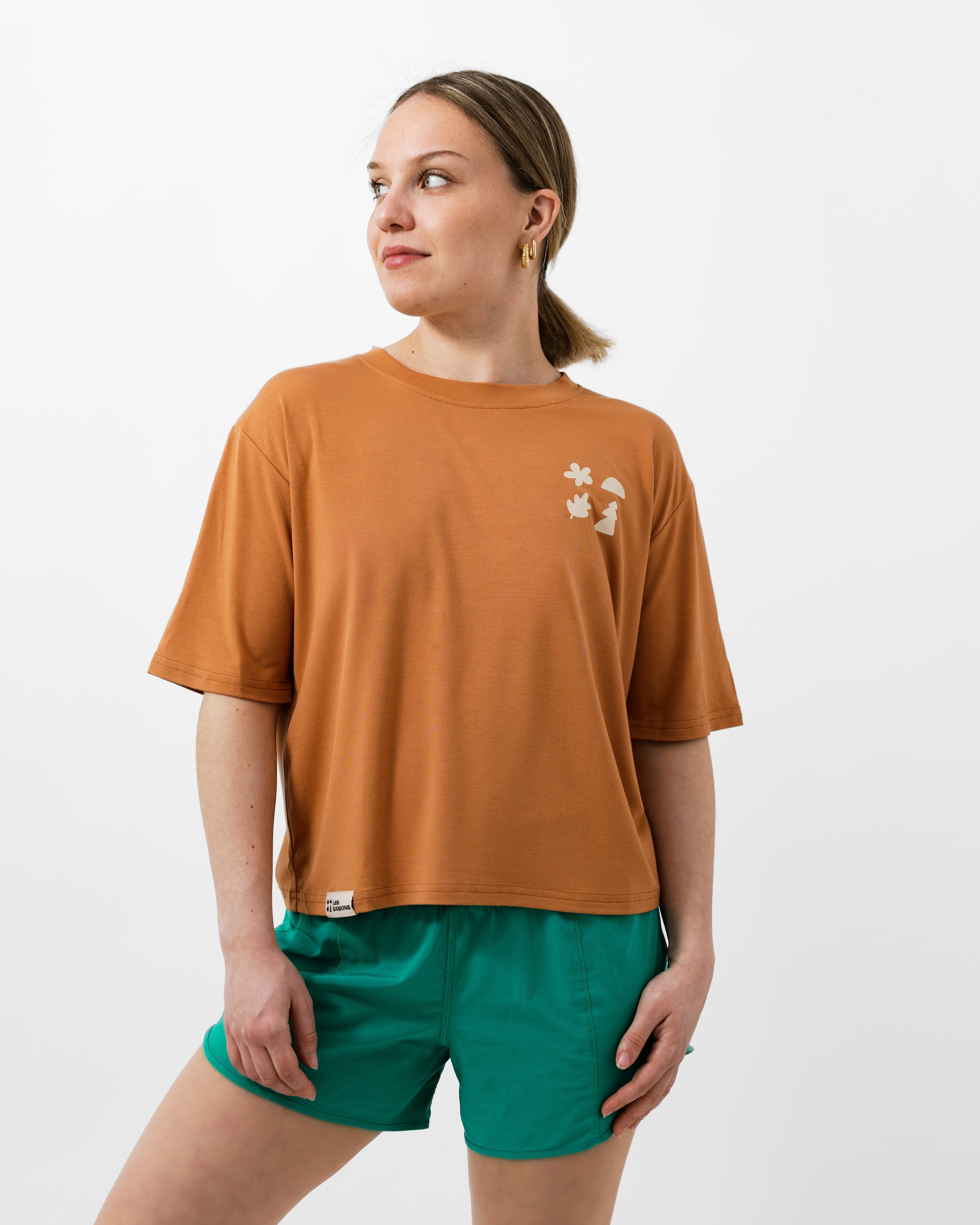 Woman wearing a brown t-shirt and green shorts on a white background