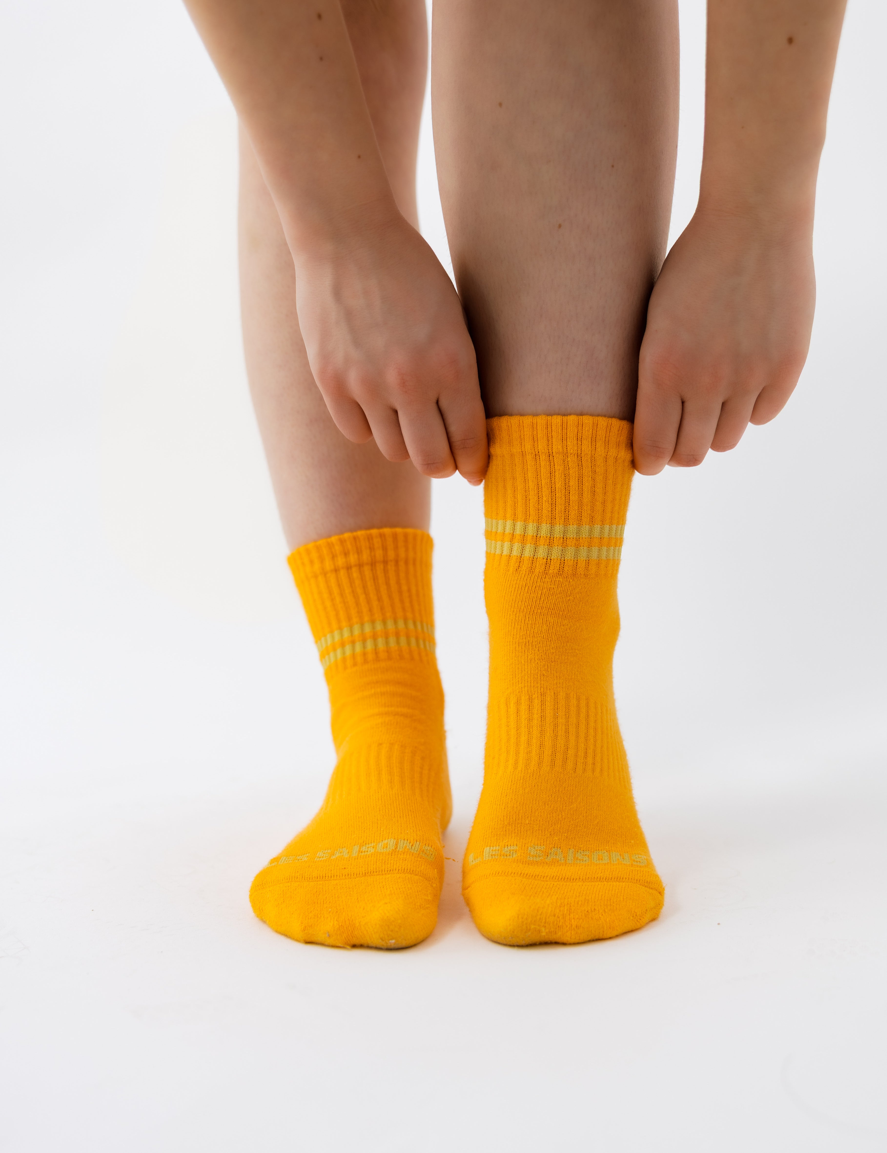 Person wearing bright orange socks with stripes on a white background