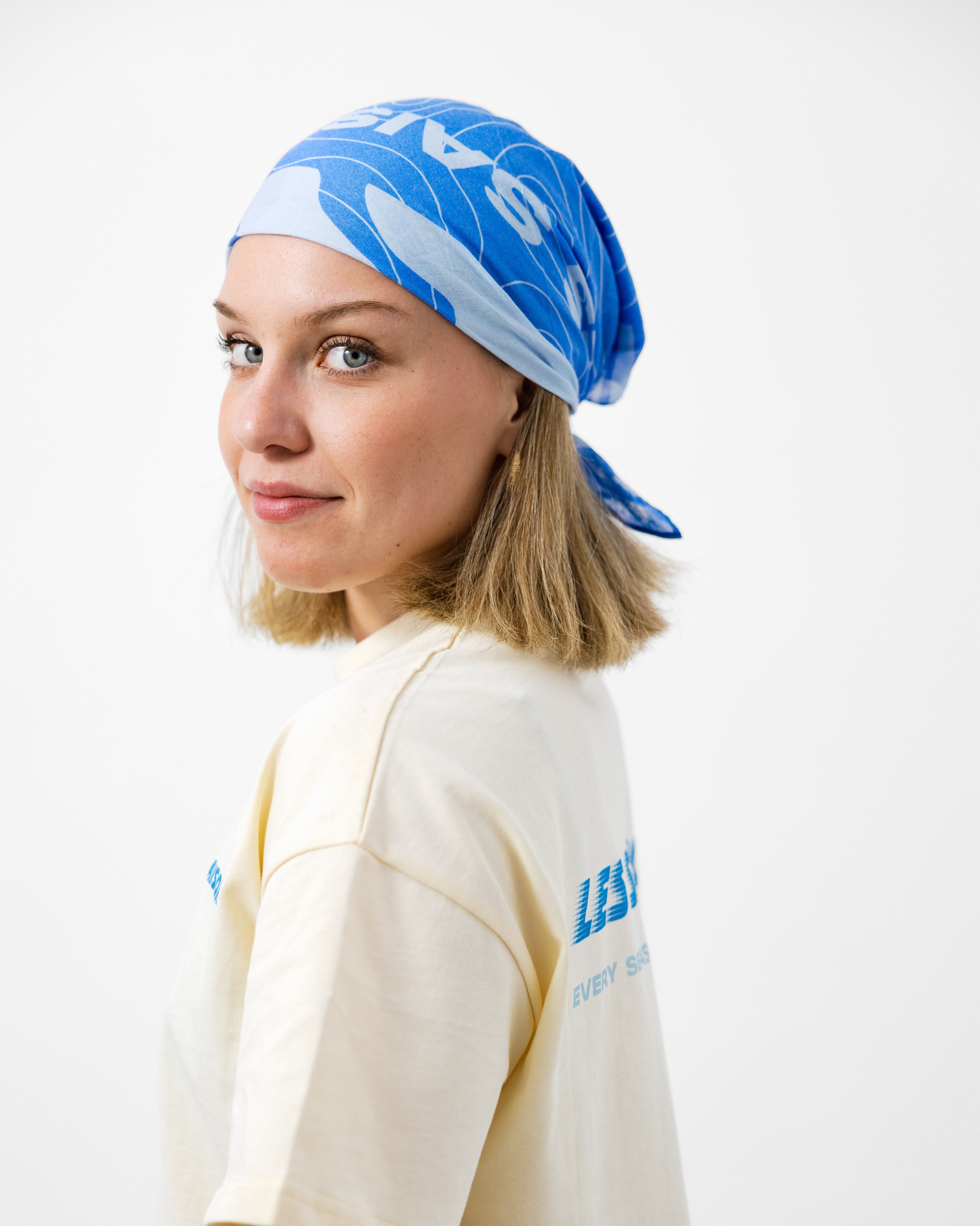 Person wearing a blue bandana and beige t-shirt with text on a white background