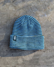 Blue beanie Les Saisons on a textured gray surface