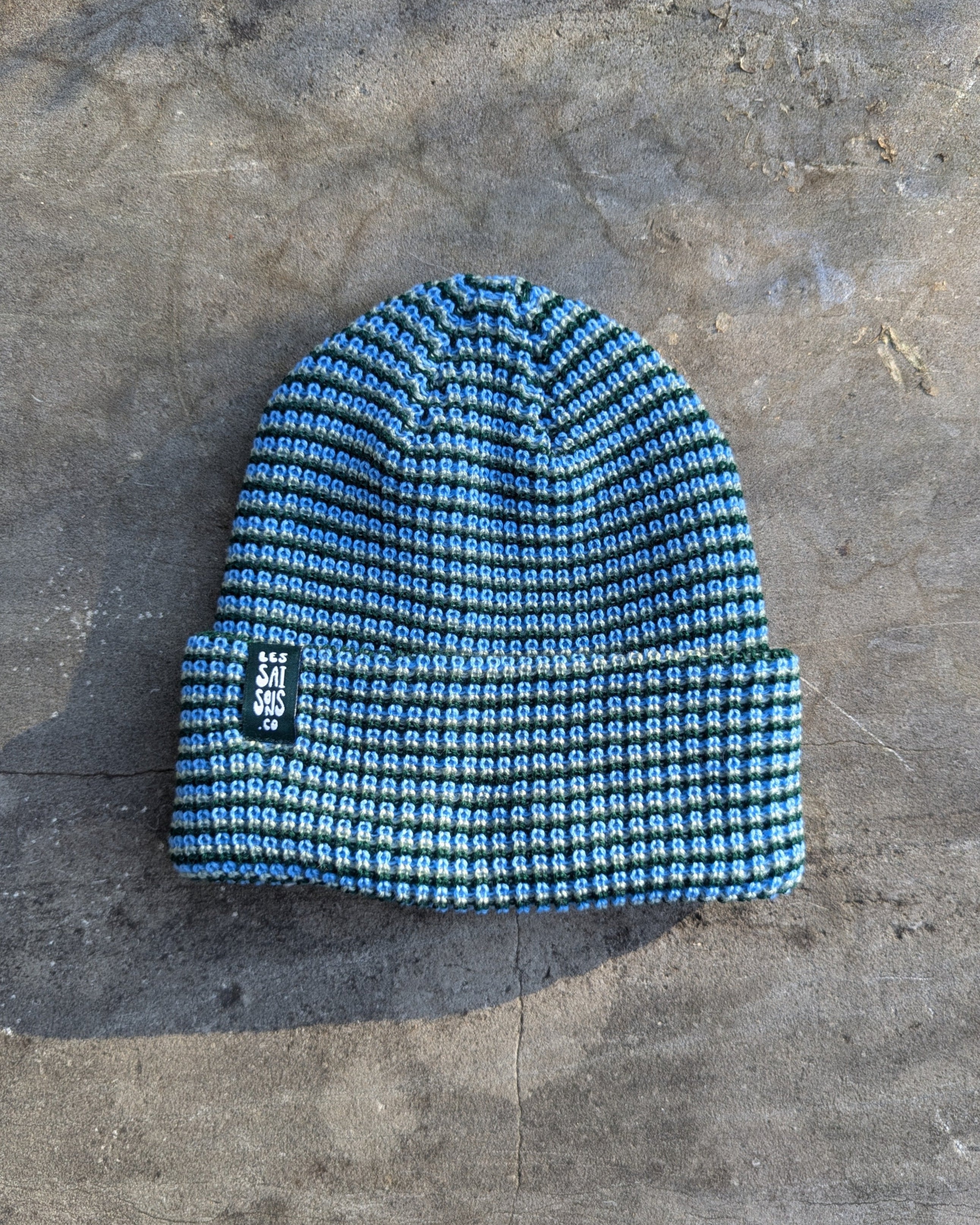 Blue beanie Les Saisons on a textured gray surface