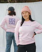 Two people wearing pink  longsleeve sweatshirts with visible branding les Saisons against a white backdrop.