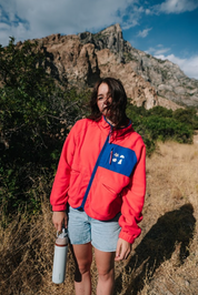 Women wearing a retro Pink jacket  les saisons with a blue zipper in a mountainous landscape