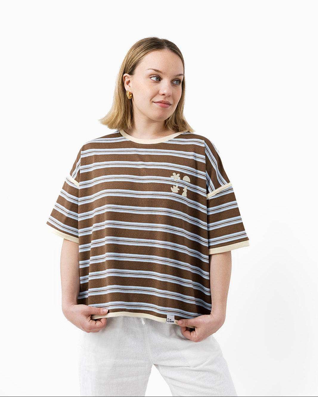 Woman wearing a brown and butter striped t-shirt with small les Saisons icons logo 