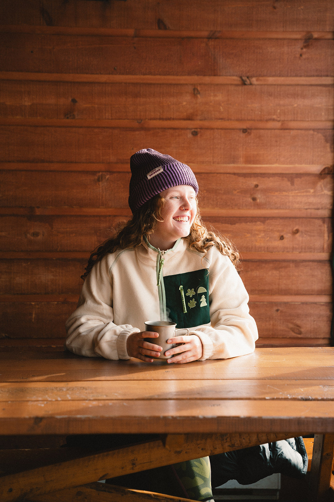 girl sitting in a ski shack wearing the Les saisons beige fleece jacket at a table