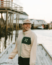 Woman standing on a dock by a body of water with a building in the background