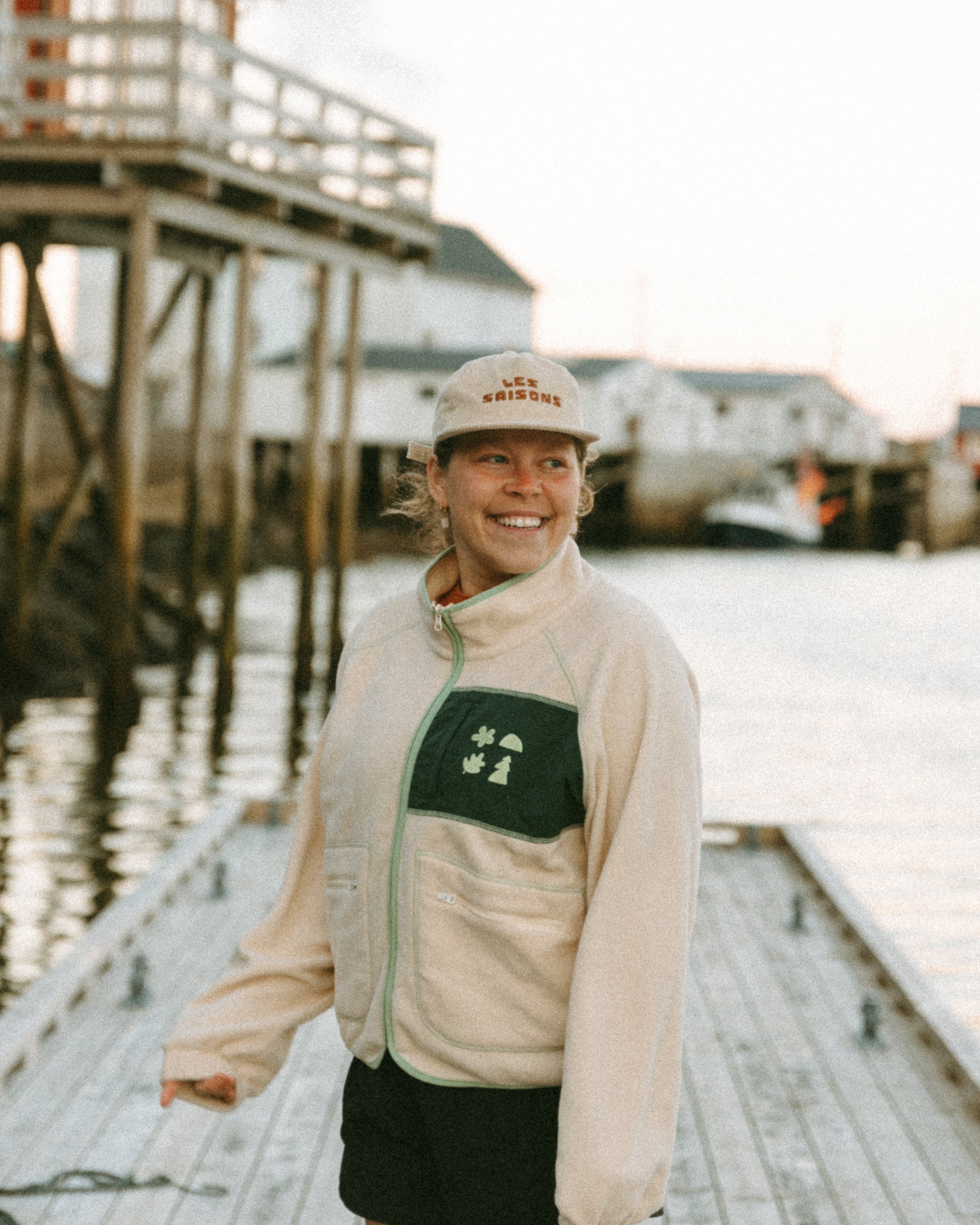 Woman standing on a dock by a body of water with a building in the background