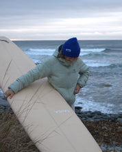 Person holding a surfboard by the ocean on a cloudy day