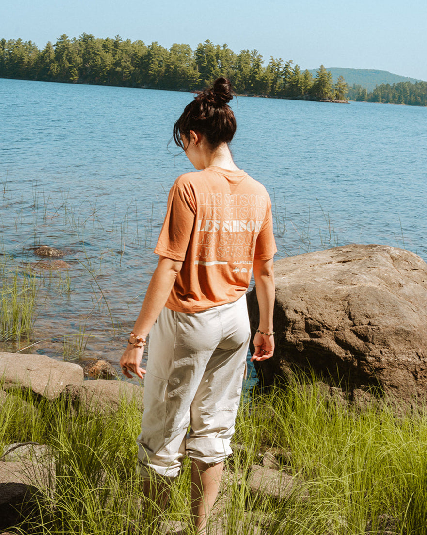 Woman standing by a lake with trees in the background_ With a Brown crop t-shirt les Saisons