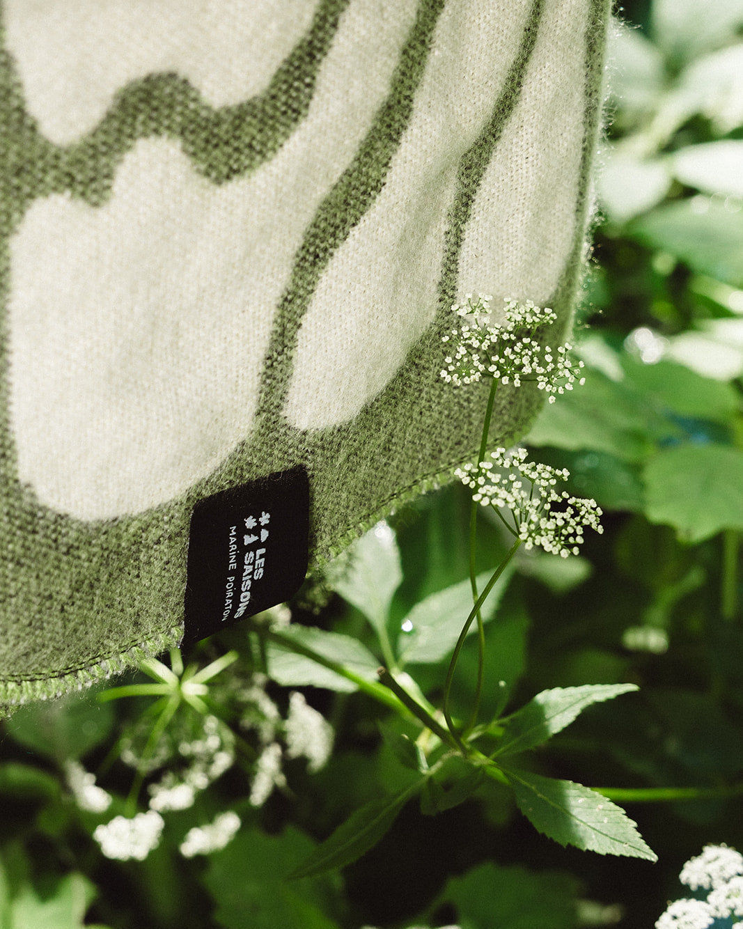 Close up of the Matcha Eternal Sunshine Blanket with logo LES SAISONS and white flowers