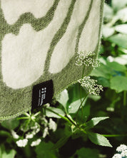 Close up of the Matcha Eternal Sunshine Blanket with logo LES SAISONS and white flowers