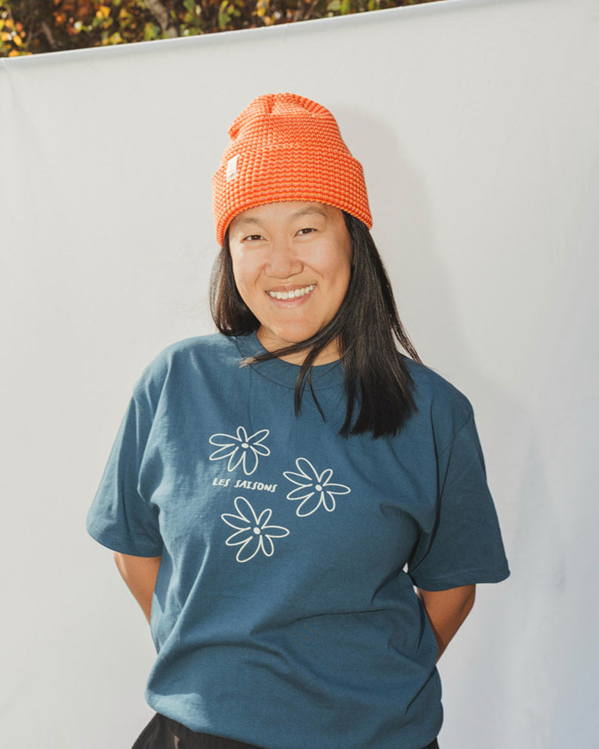 Woman wearing striped light orange and orange beanie with blue t-shirt