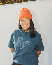 Woman wearing striped light orange and orange beanie with blue t-shirt