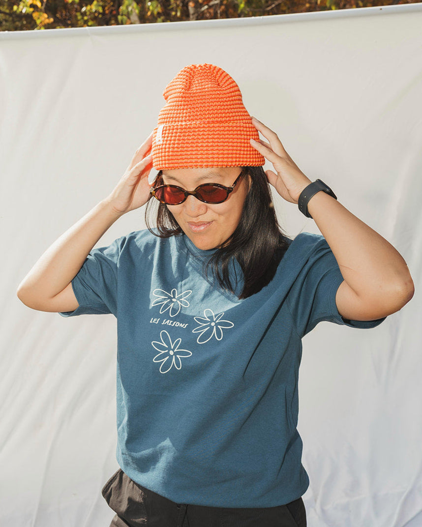 Woman wearing striped light-orange and orange beanie with blue t-shirt