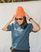 Woman wearing striped light-orange and orange beanie with blue t-shirt