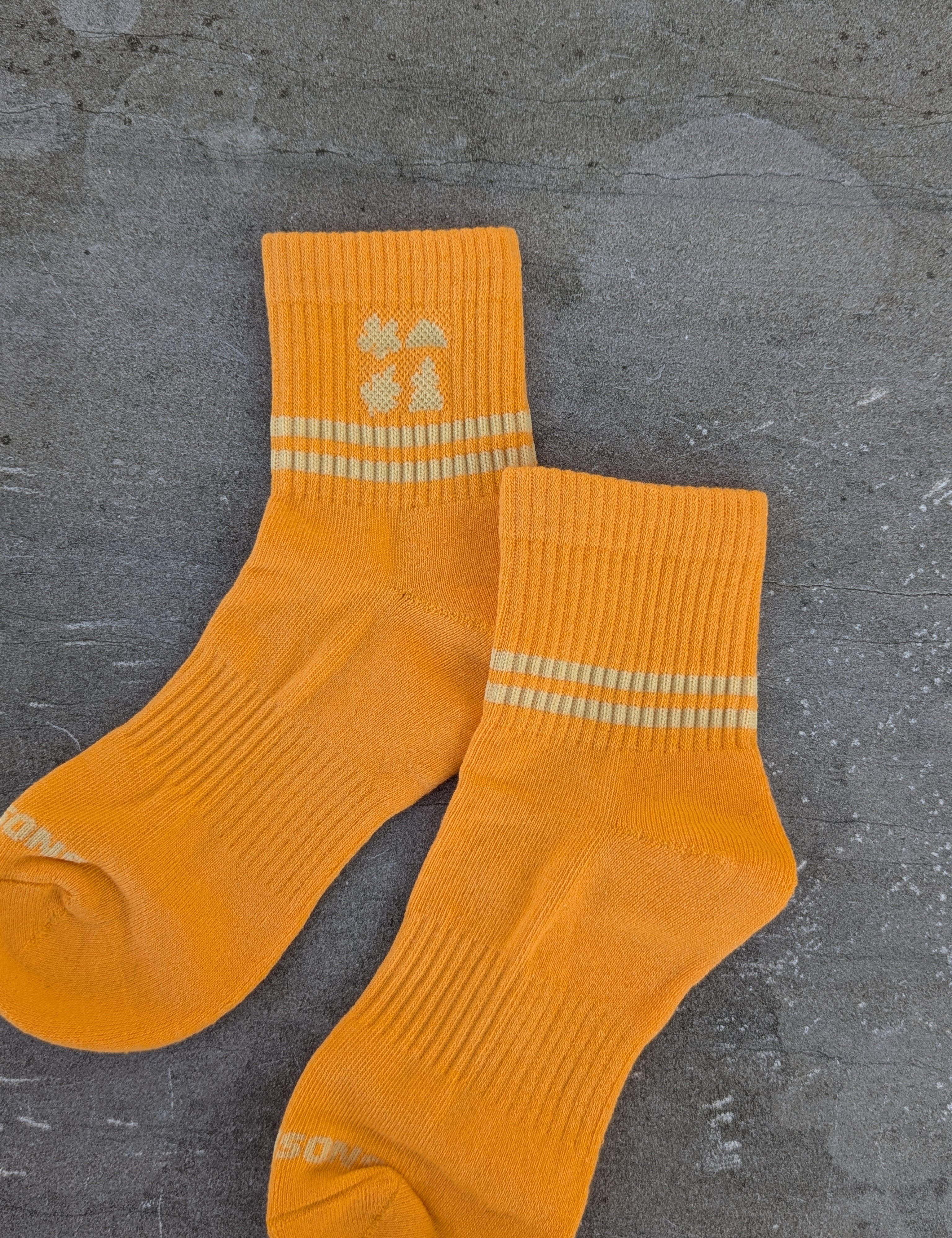 Orange socks with Cream stripes on a gray surface